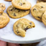 Cookies on a marble top cake stand with the front cookie having a big bite taken out of it