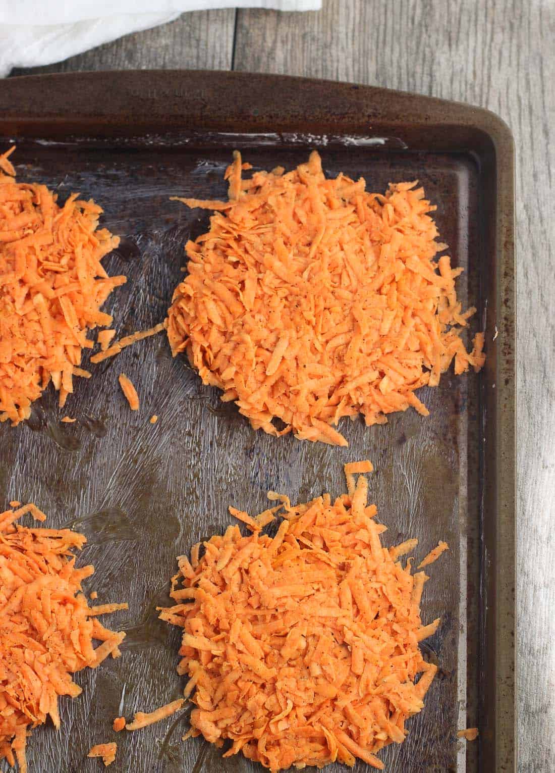 Shredded sweet potato arranged into patties on a greased baking sheet.