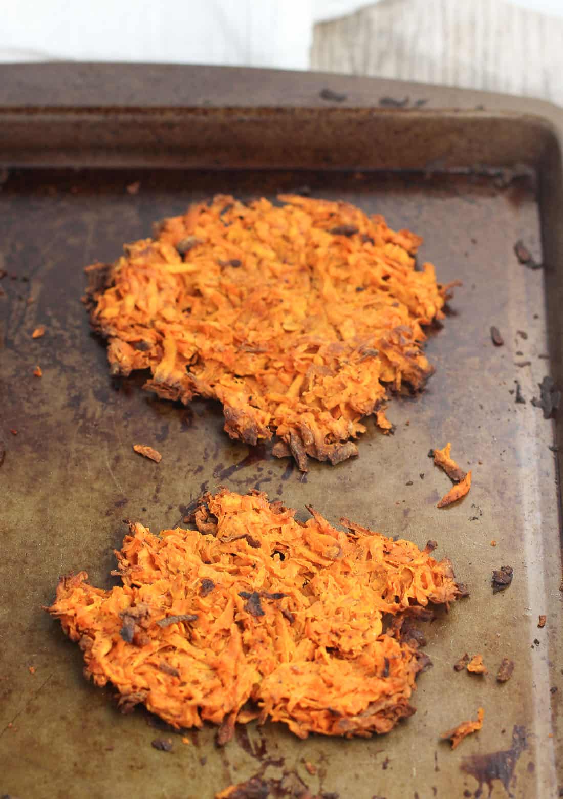 Cooked hash brown patties on a metal baking sheet.