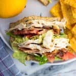 An overhead view of a sandwich section on a plate with an orange and chips.