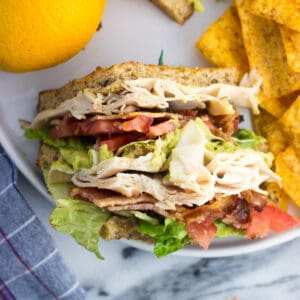 An overhead view of a sandwich section on a plate with an orange and chips.