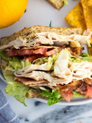 An overhead view of a sandwich section on a plate with an orange and chips.