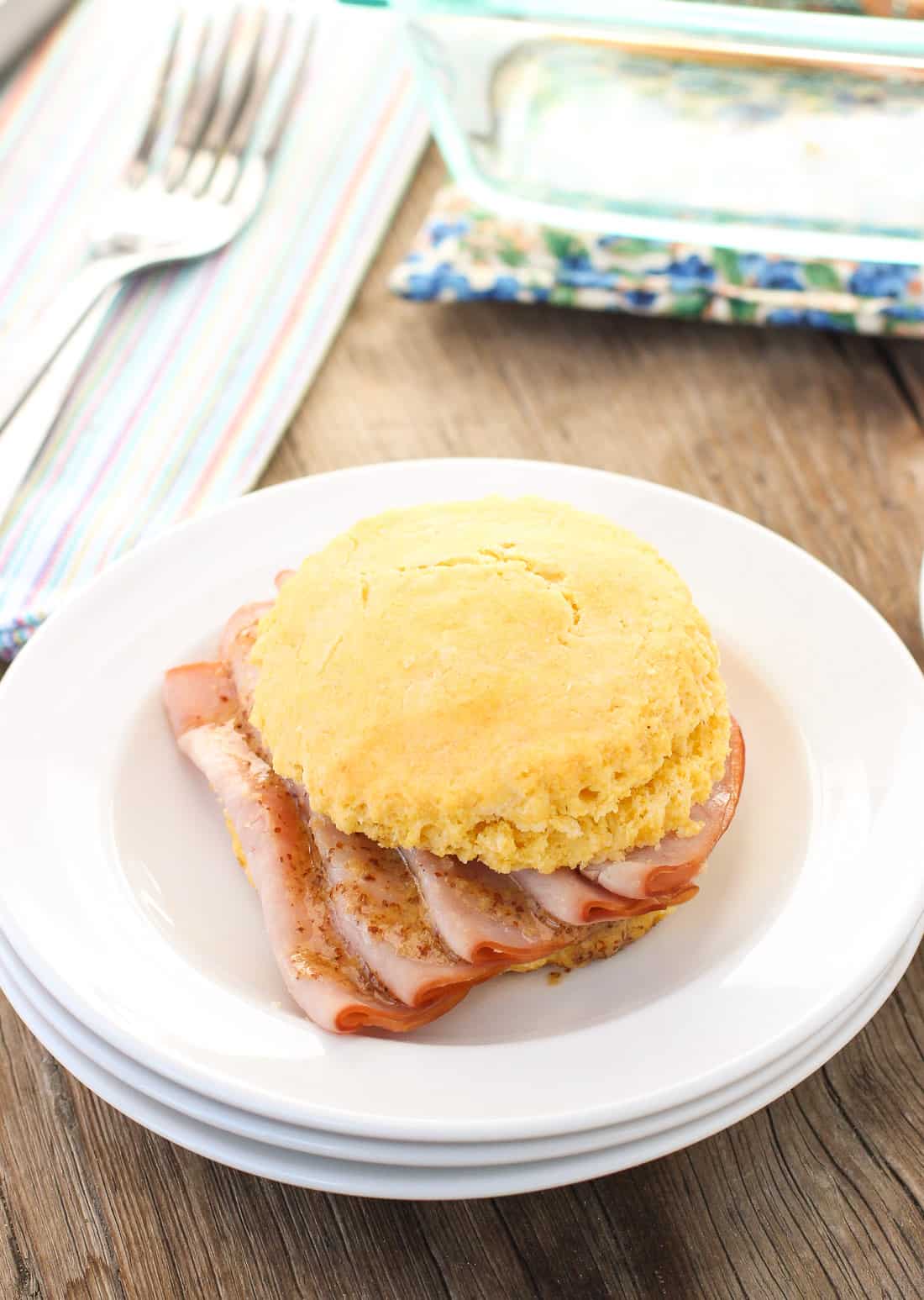 A sandwich on a small plate in front of the tray of them.