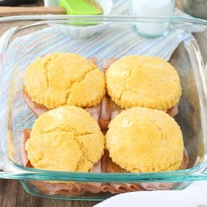 Four cornmeal biscuit sandwiches assembled in a square glass dish.