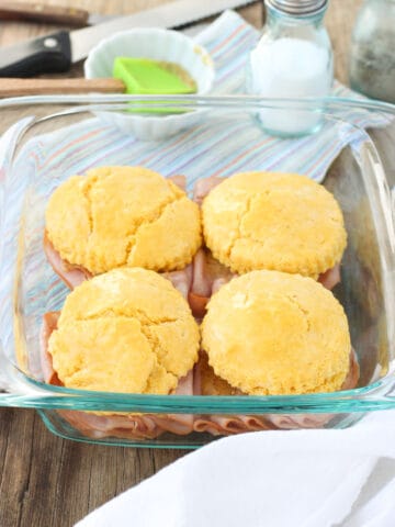 Four cornmeal biscuit sandwiches assembled in a square glass dish.
