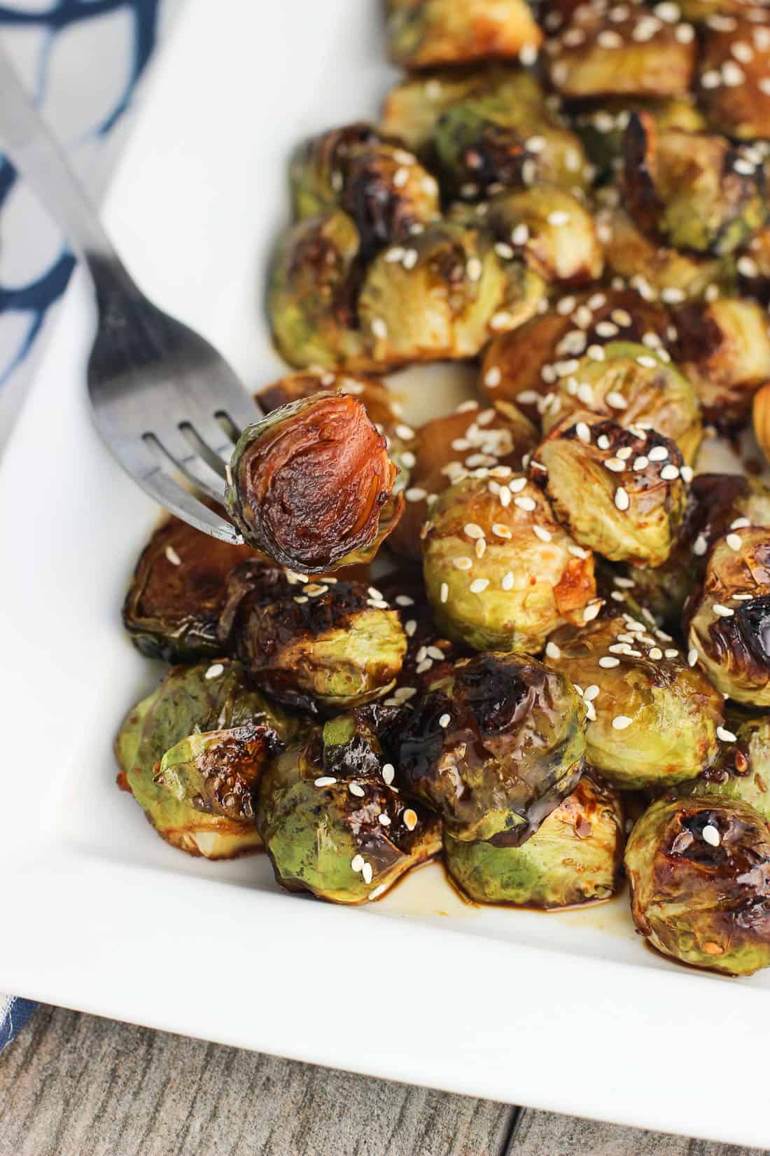 A fork spearing a Brussels sprouts half from the tray showing the deeply roasted surface