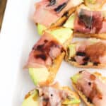 Prosciutto avocado crostini lined up on a serving tray.