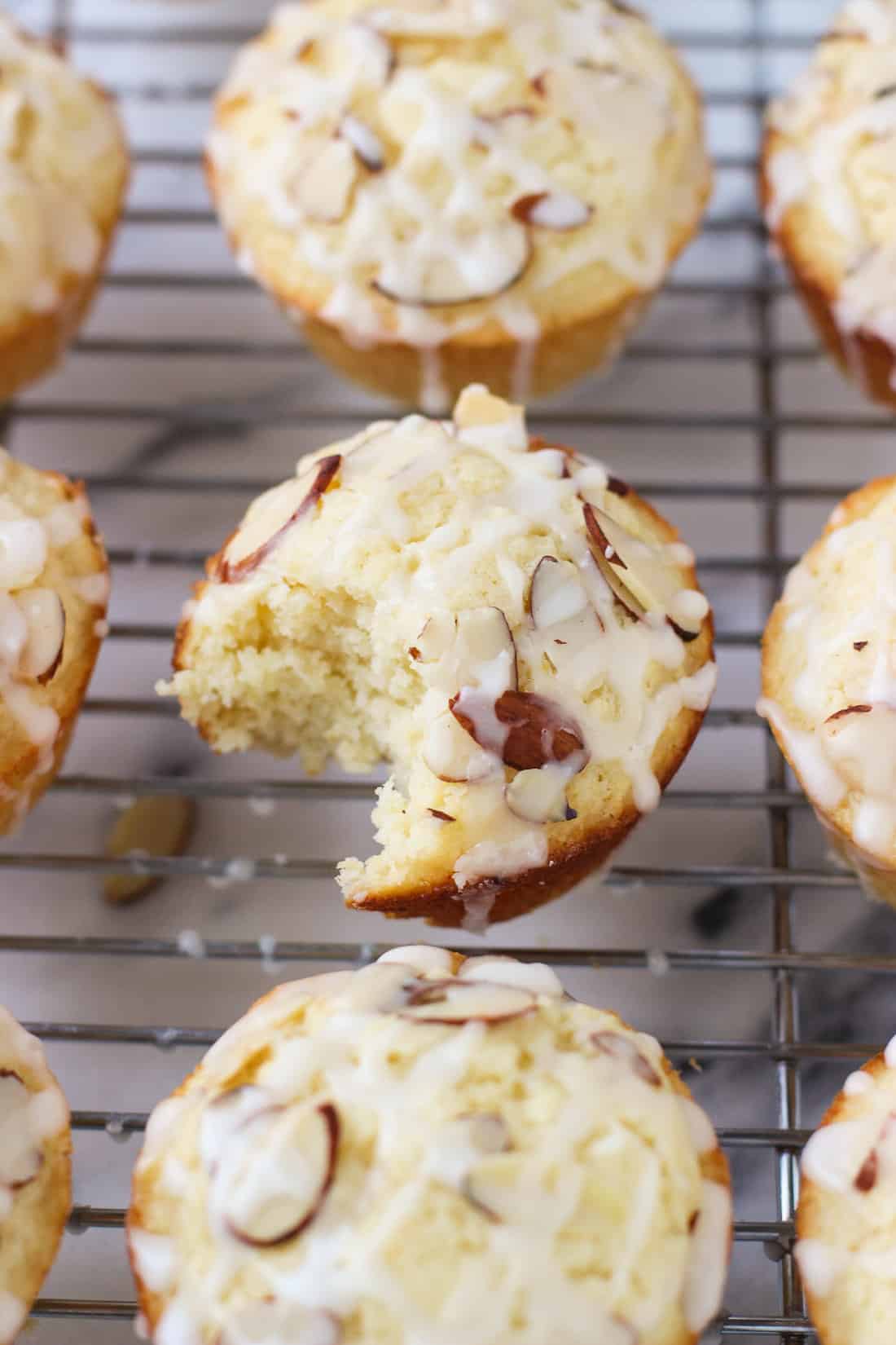 Baked muffins on a wire cooling rack with a big bite taken out of one.