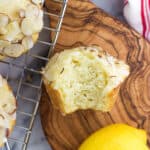 An overhead shot of a lemon ricotta muffin with a bite taken out of it on a small wooden serving board