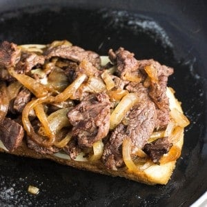 An open face cheesesteak panini in a skillet.