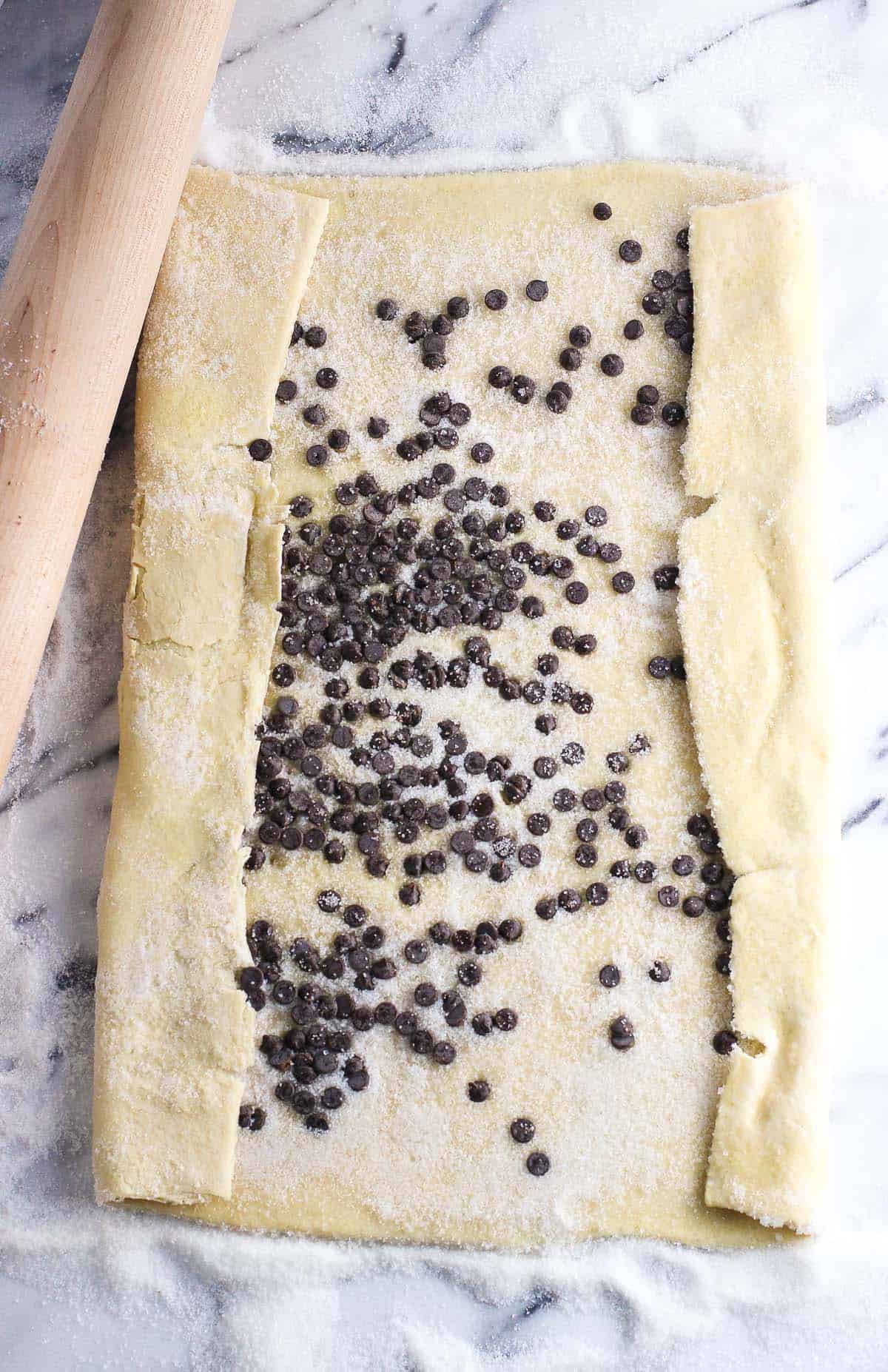 Mini chocolate chips spread onto a sugar-coated sheet of puff pastry