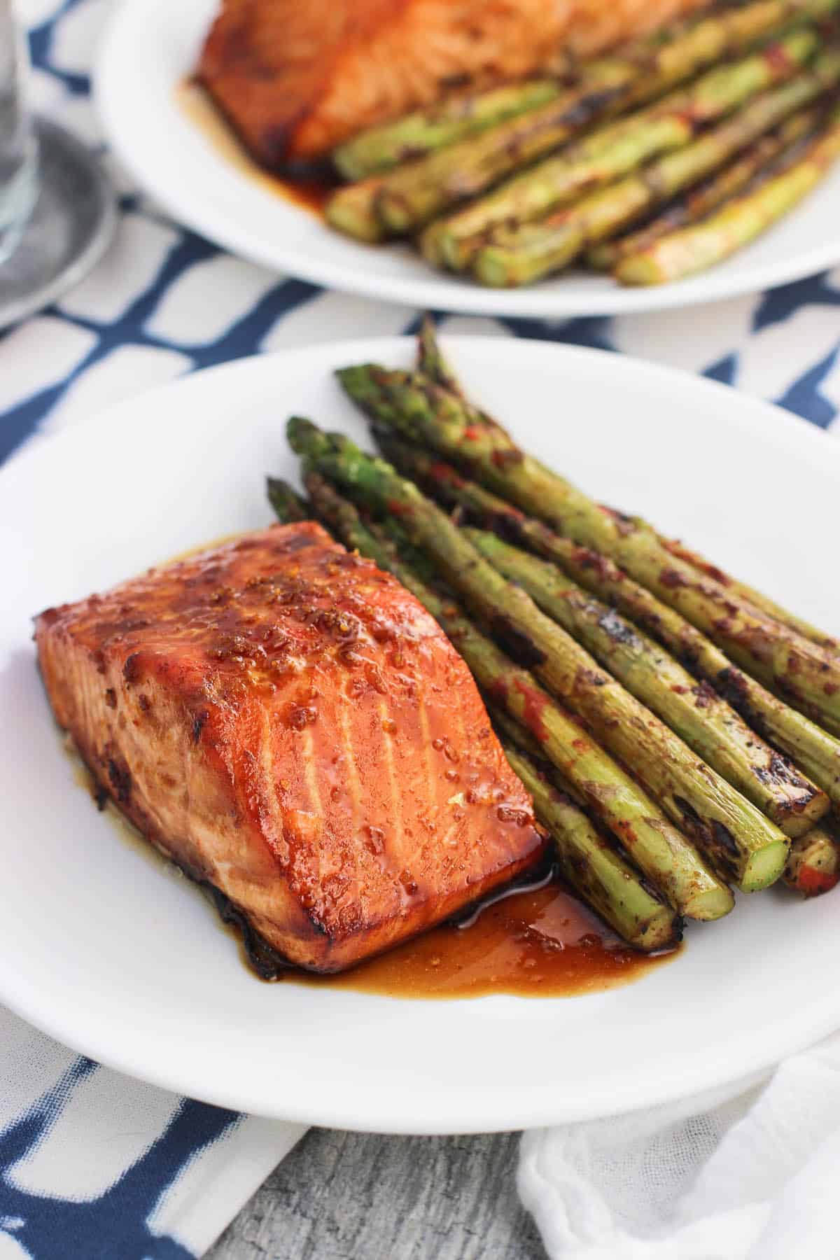 A salmon fillet, sauce, and asparagus on a plate.