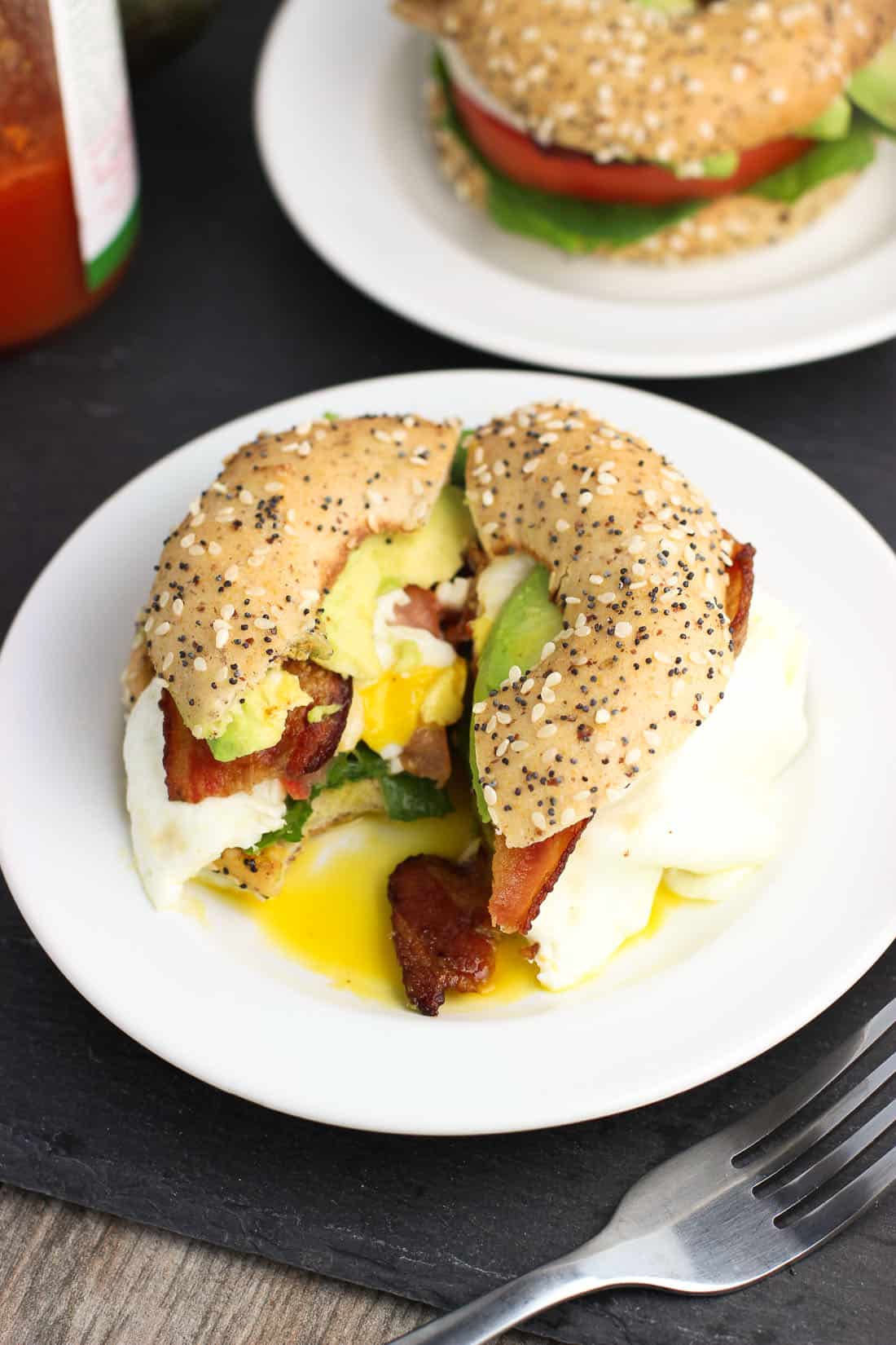 A bagel thin BLT sandwich with a big bite taken out of one of the halves