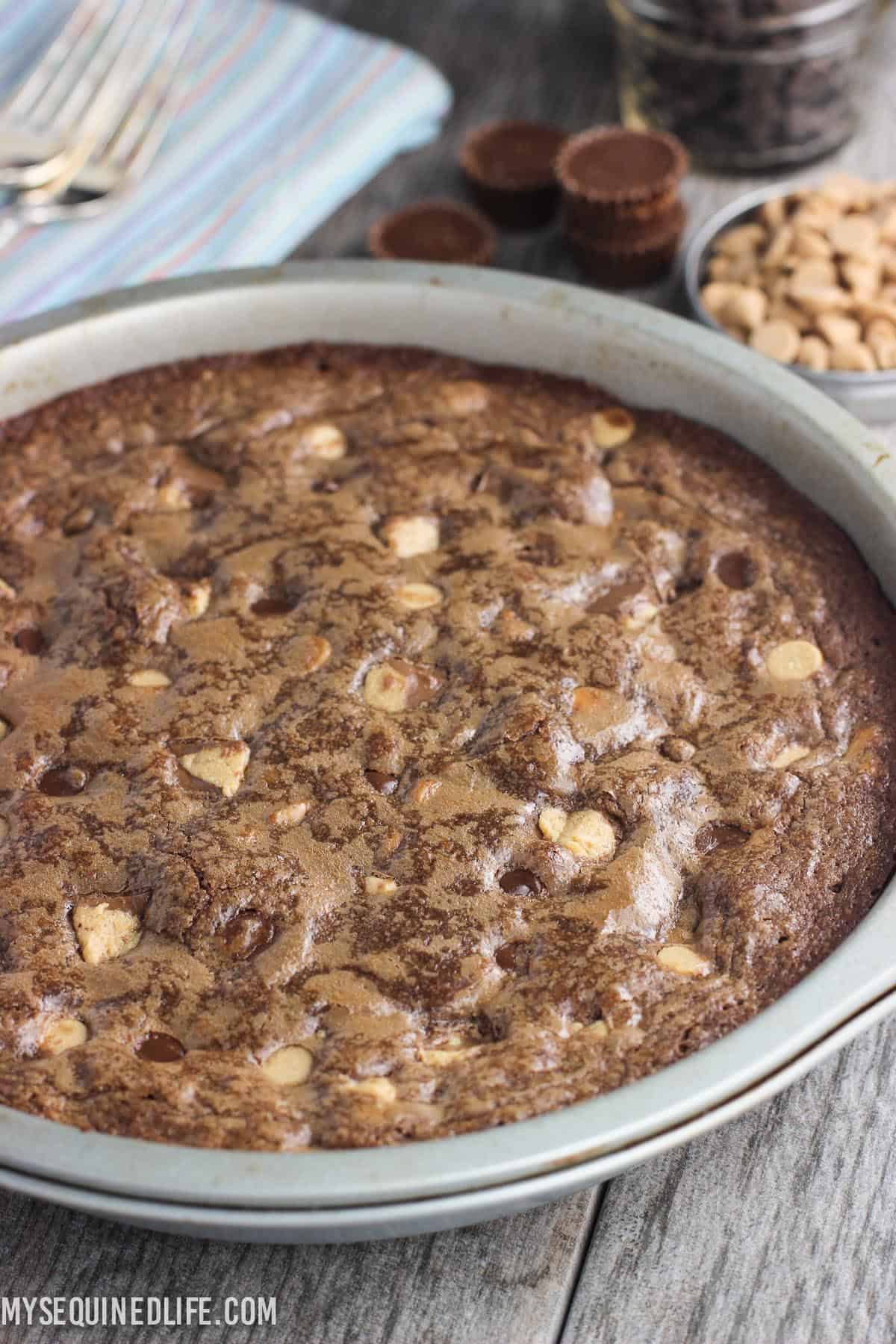 A cooked brownie pie in a round metal cake pan.