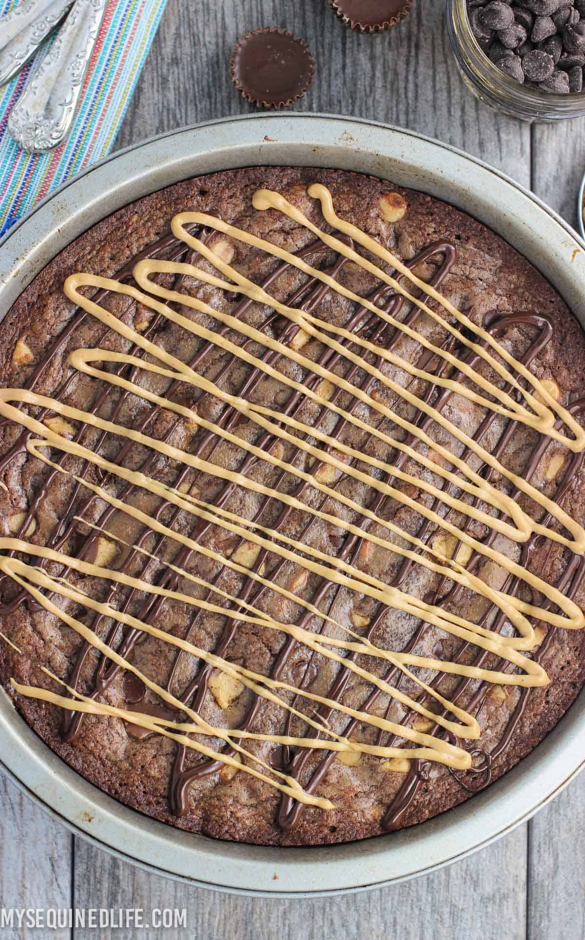 Melted chocolate and peanut butter chips drizzled over a brownie cake in its pan.