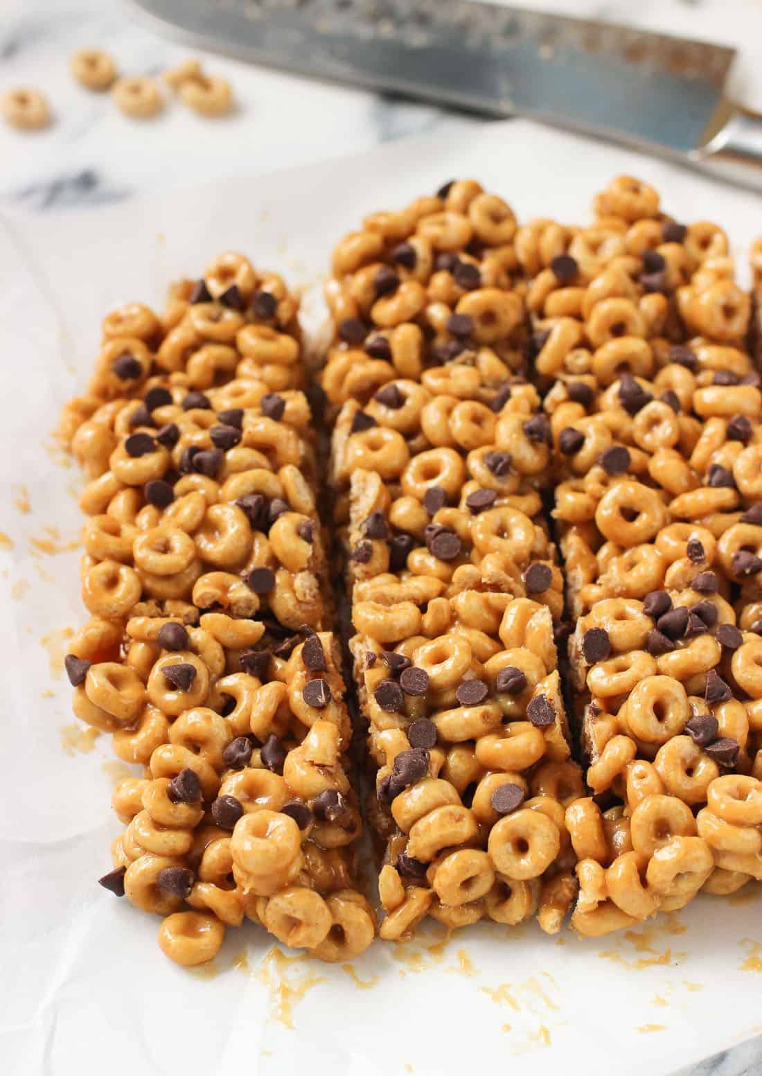 A slab of sliced cereal bars on a piece of parchment paper with a knife in the background