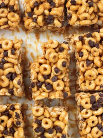 An overhead shot of cereal bars sliced on a board with a bite taken out of the corner of the middle bar