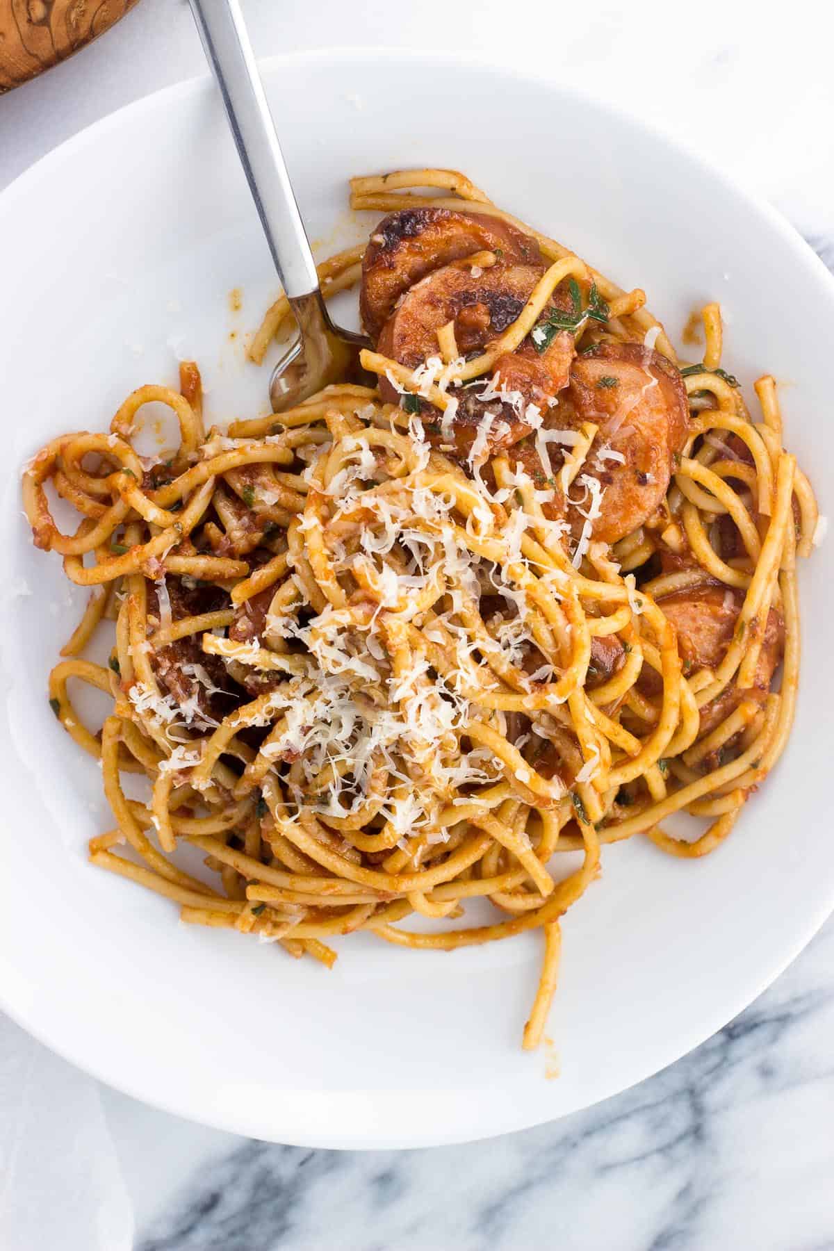 A ceramic pasta bowl of a portion of smoked sausage fra diavolo topped with grated Parmesan.