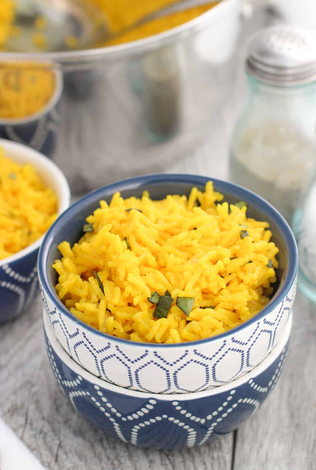 Small stacked bowls, the top one containing a serving of coconut turmeric rice.