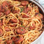 A pan full of spaghetti, fra diavolo sauce, and smoked sausage