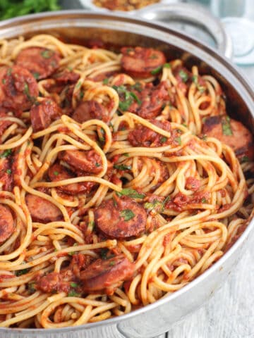 A pan full of spaghetti, fra diavolo sauce, and smoked sausage