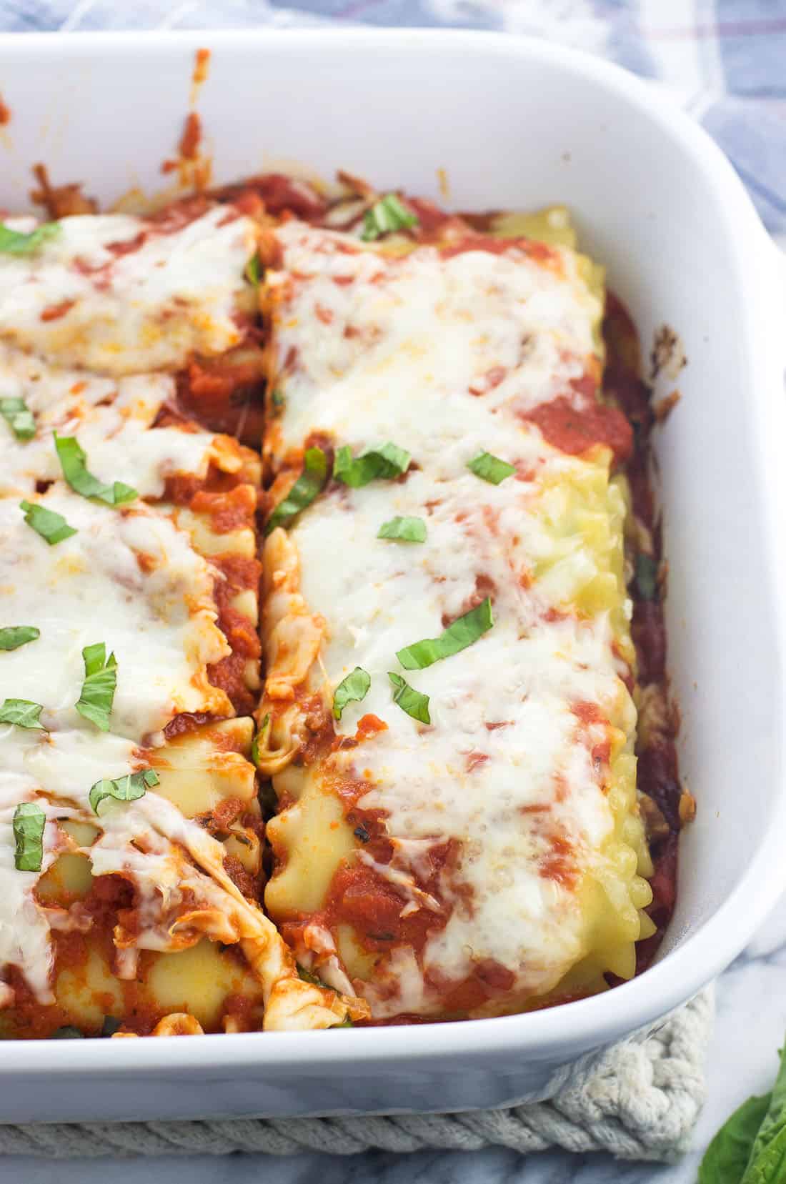 Cooked sausage lasagna rolls in a baking dish.