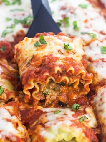 A lasagna roll being lifted out of the ban with a small spatula