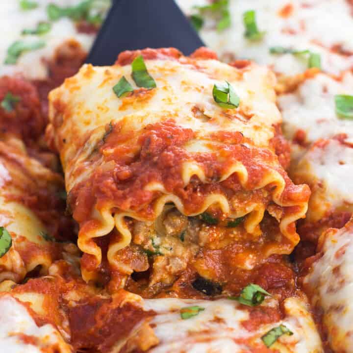 A lasagna roll being lifted out of the ban with a small spatula