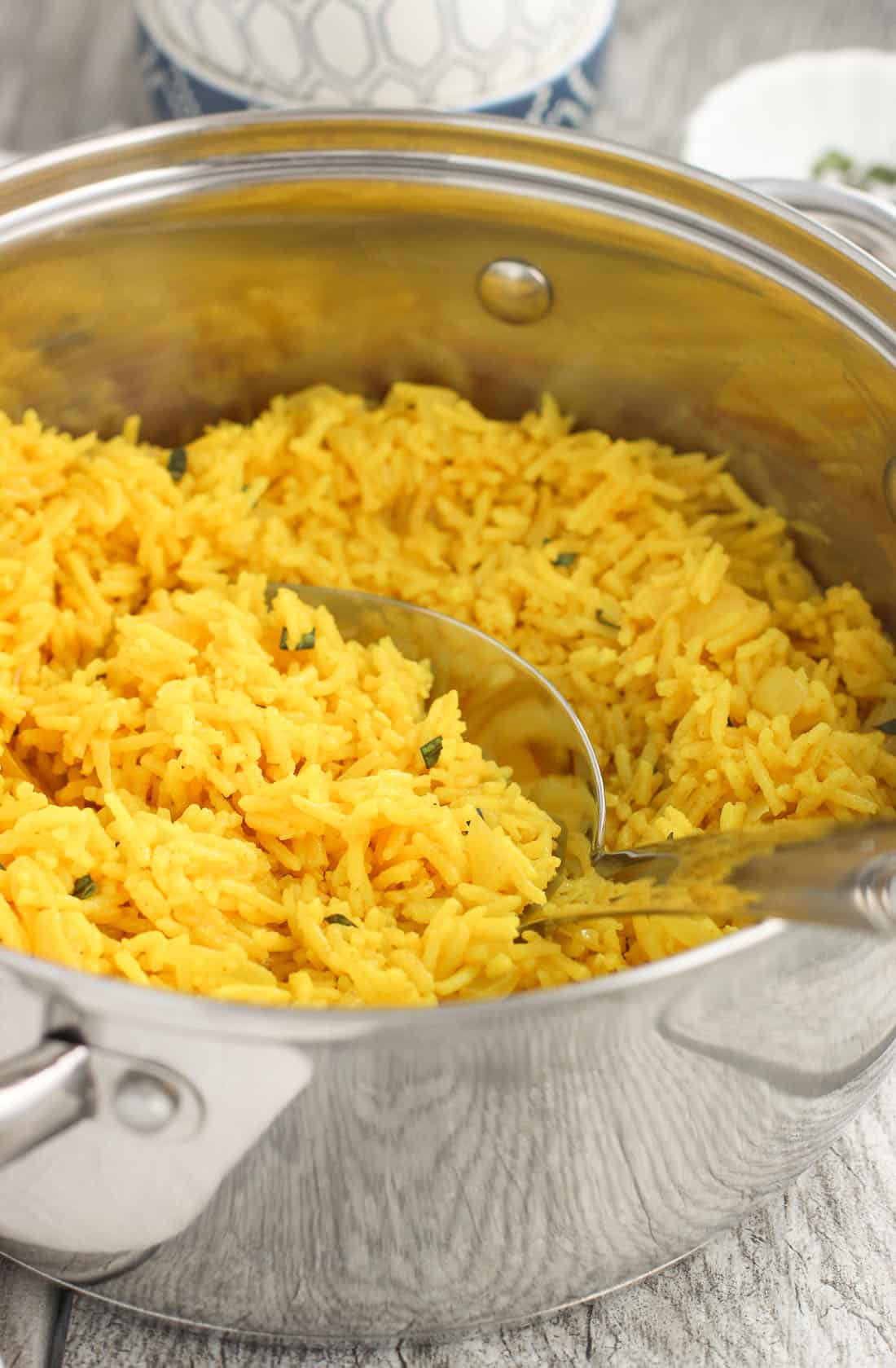 A large pot of turmeric rice with a serving spoon in it.