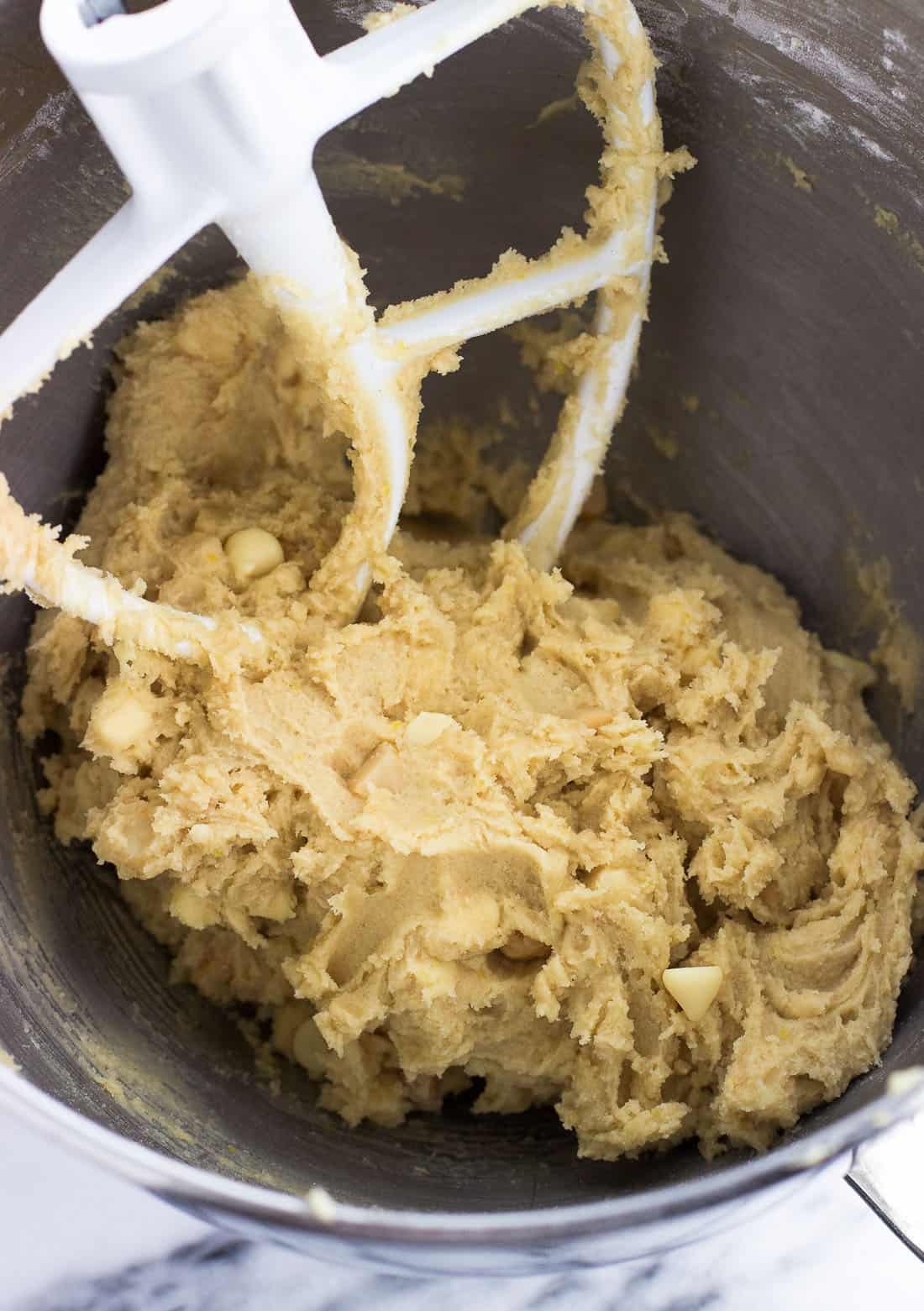 Lemon white chocolate macadamia nut cookie dough in a stand mixer bowl with the paddle attachment