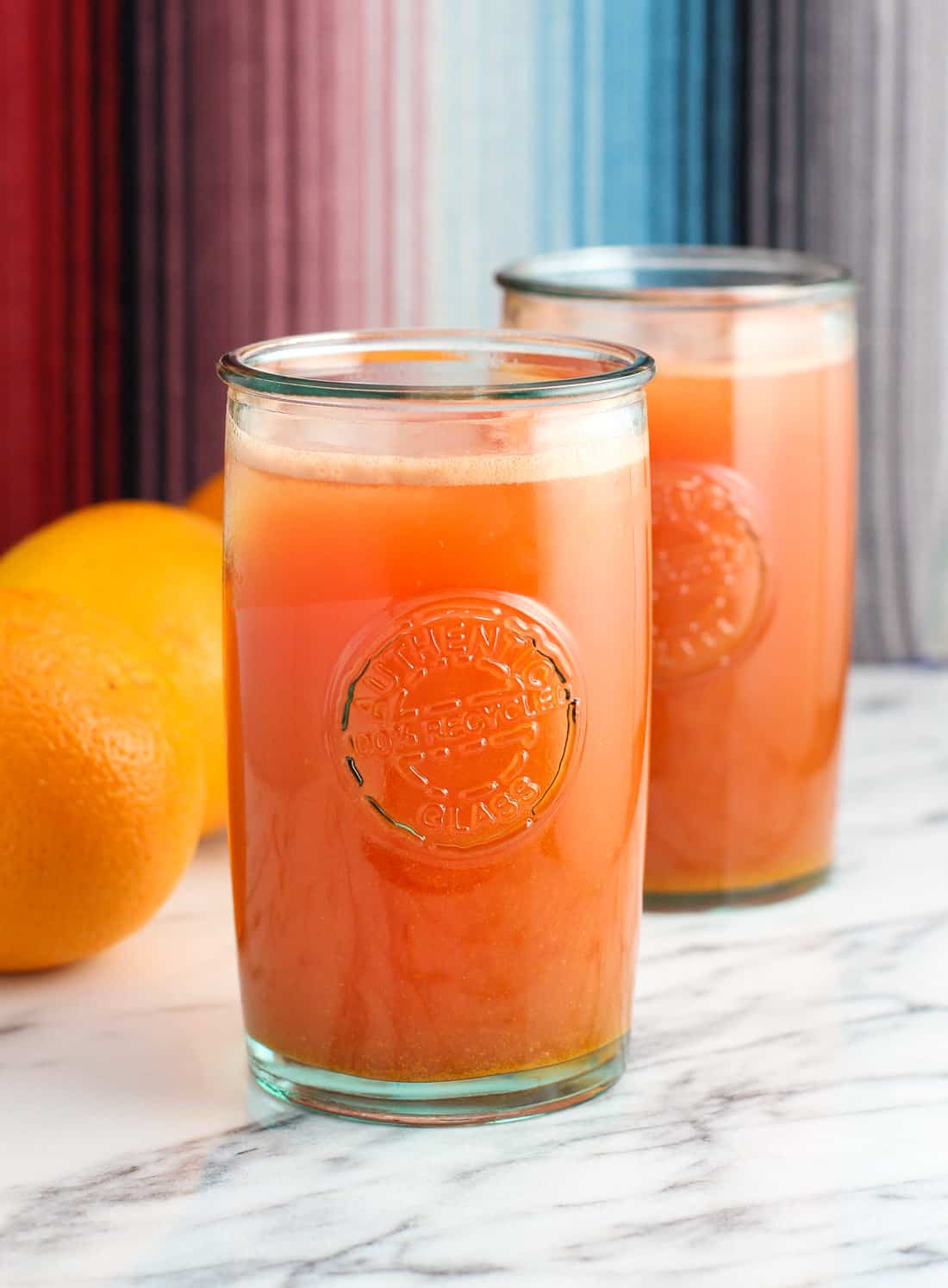 Glasses of juice with fresh oranges on a table.