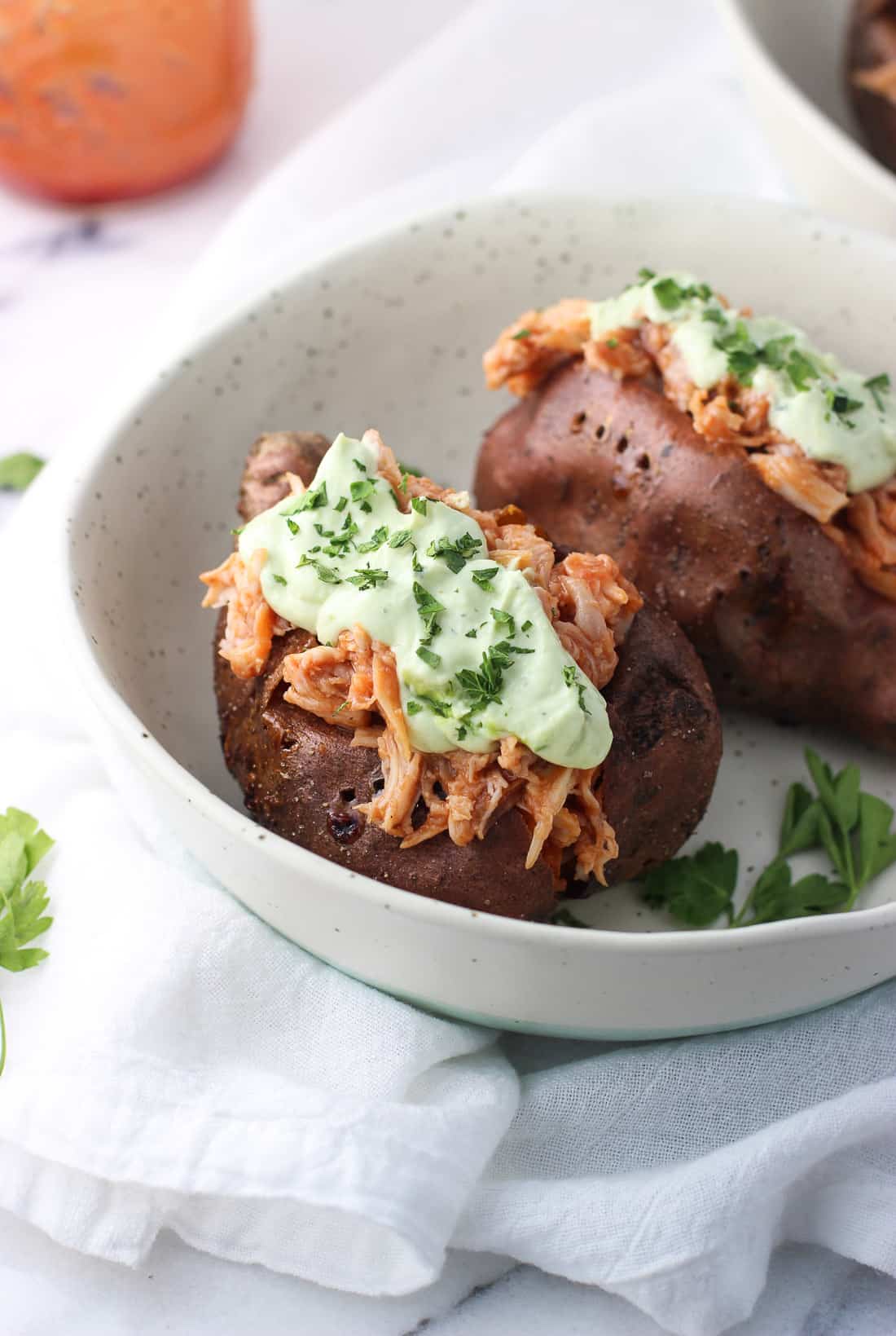 A close-up of the roasted and stuffed sweet potatoes topped with sauce.