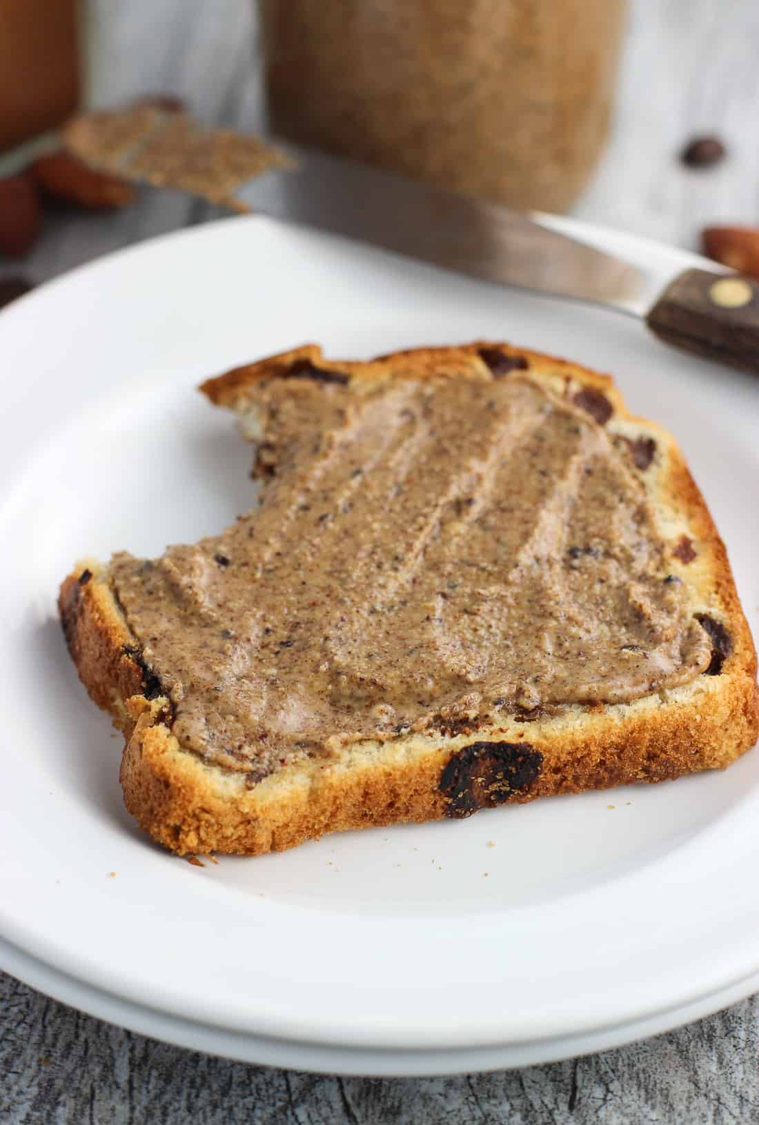 A slice of toast slathered with almond butter with a big bite taken out