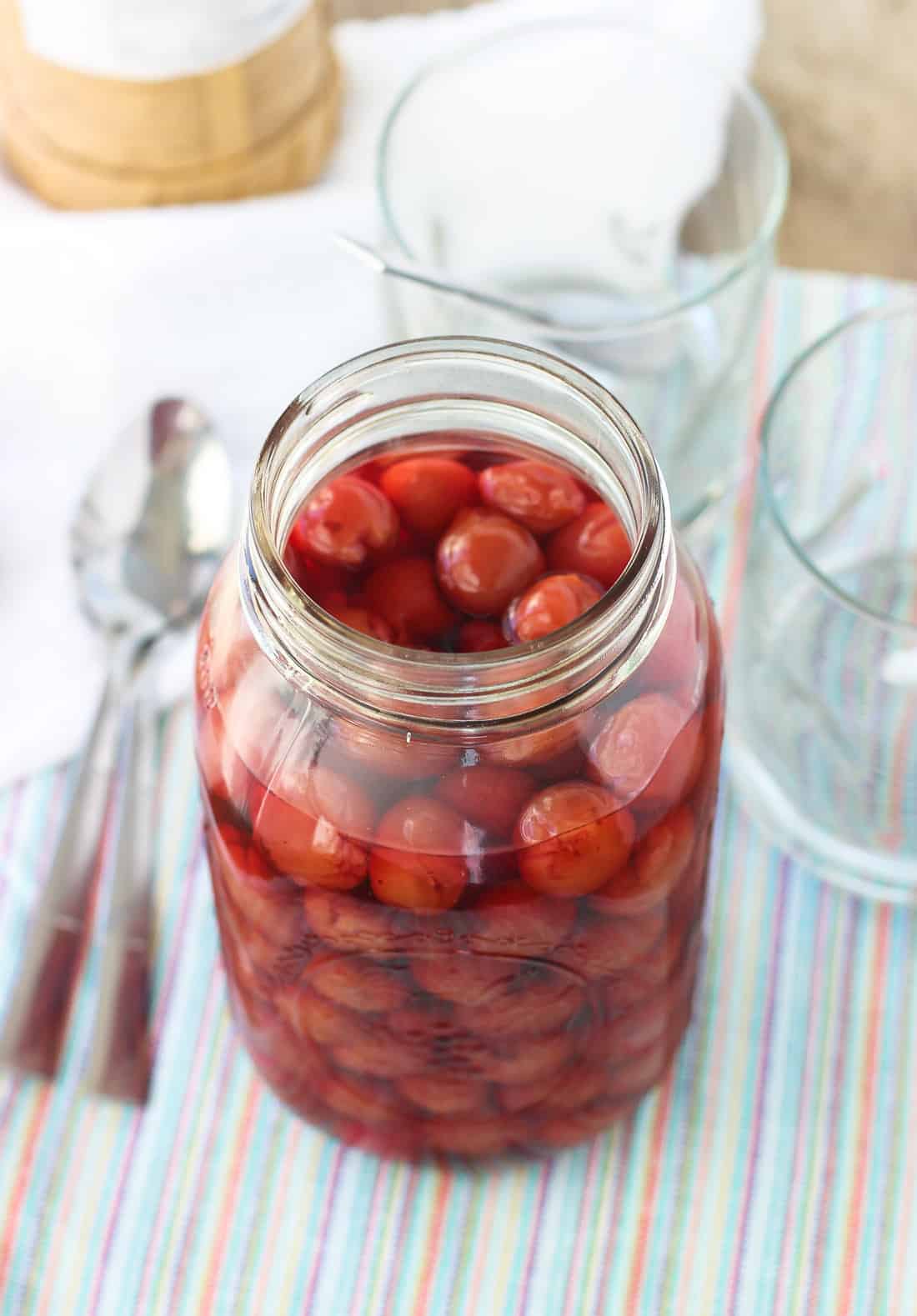 A large glass jar filled with whole cherries and maraschino liquid.