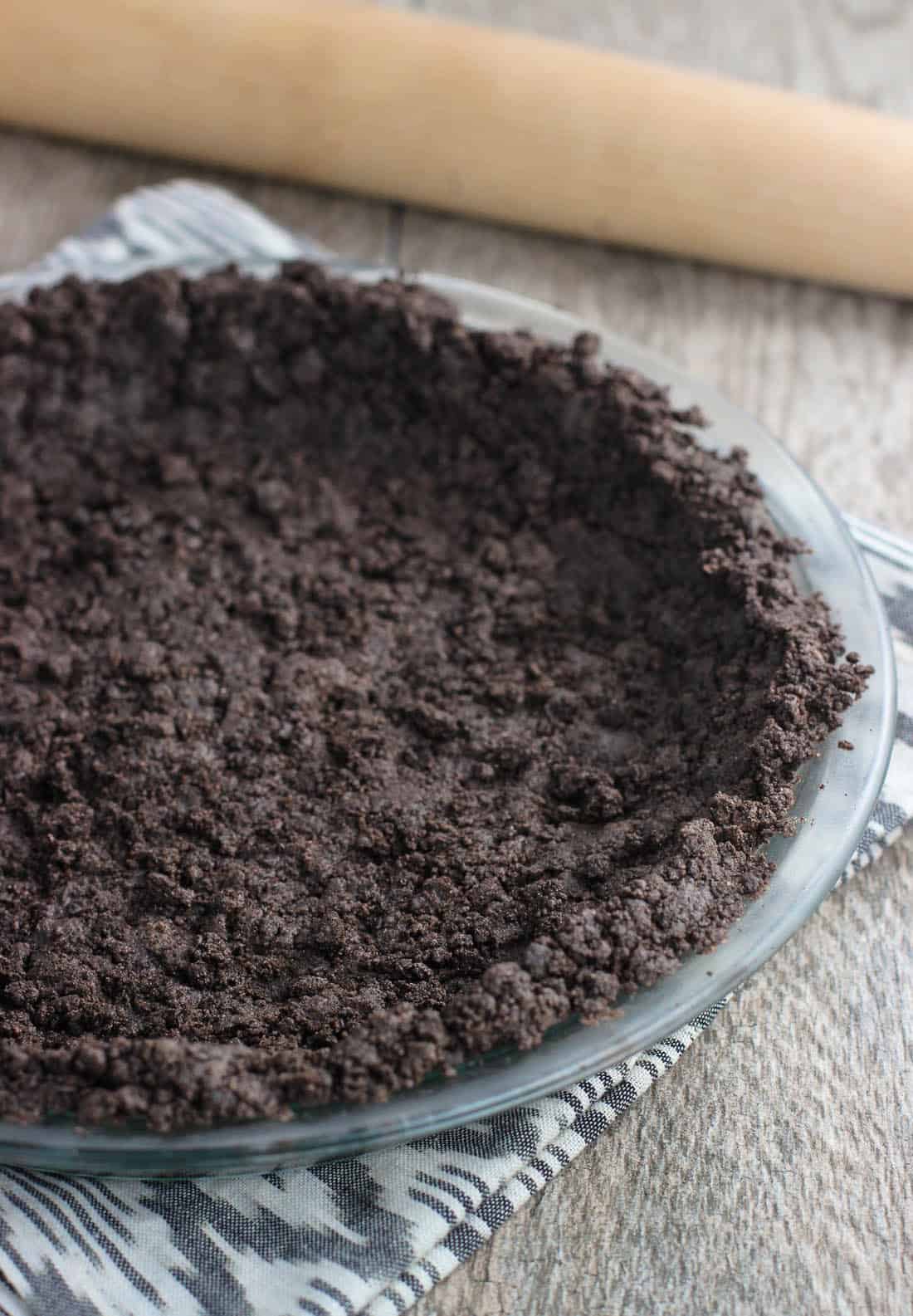 Oreo cookie crumbs pressed into a glass pie plate as a crust.