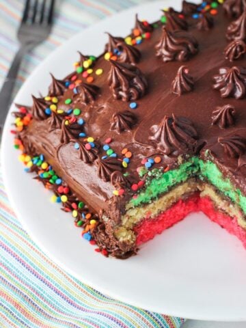 Rainbow cookie cake with a big piece removed to show the layers.