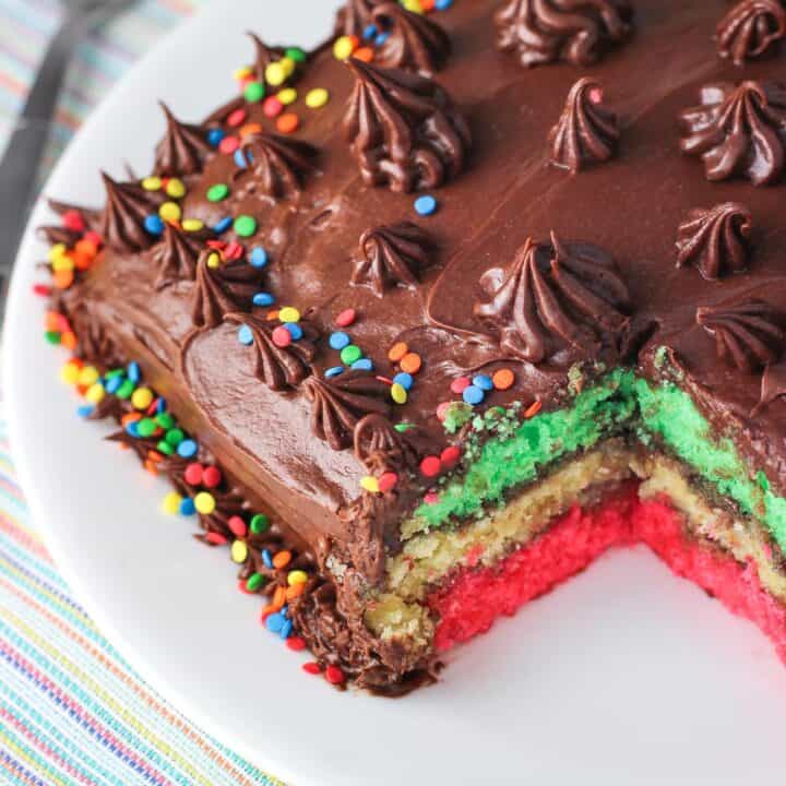 Rainbow cookie cake with a big piece removed to show the layers.