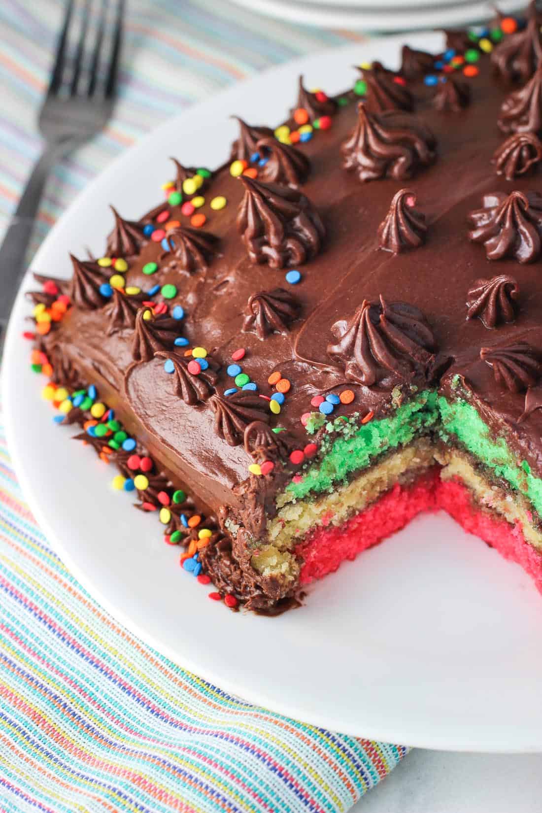 Rainbow cookie cake with a big piece removed to show the layers.