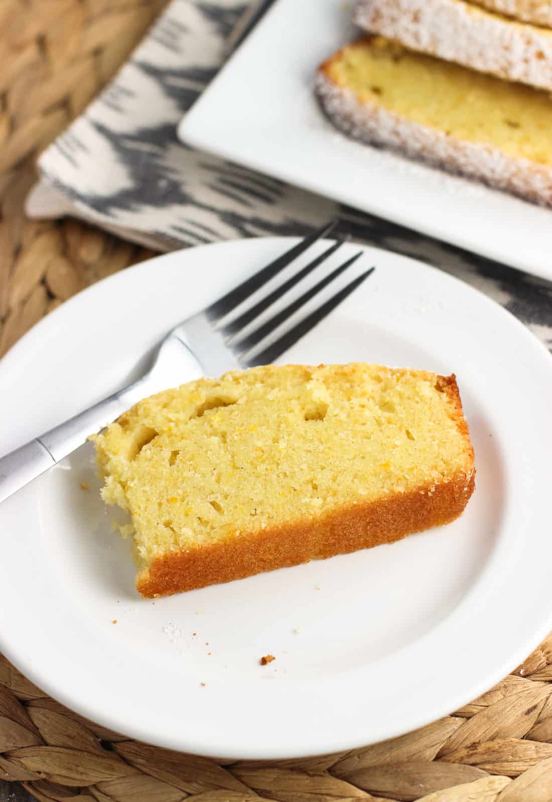 A slice of pound cake on a dessert plate with a forkful removed