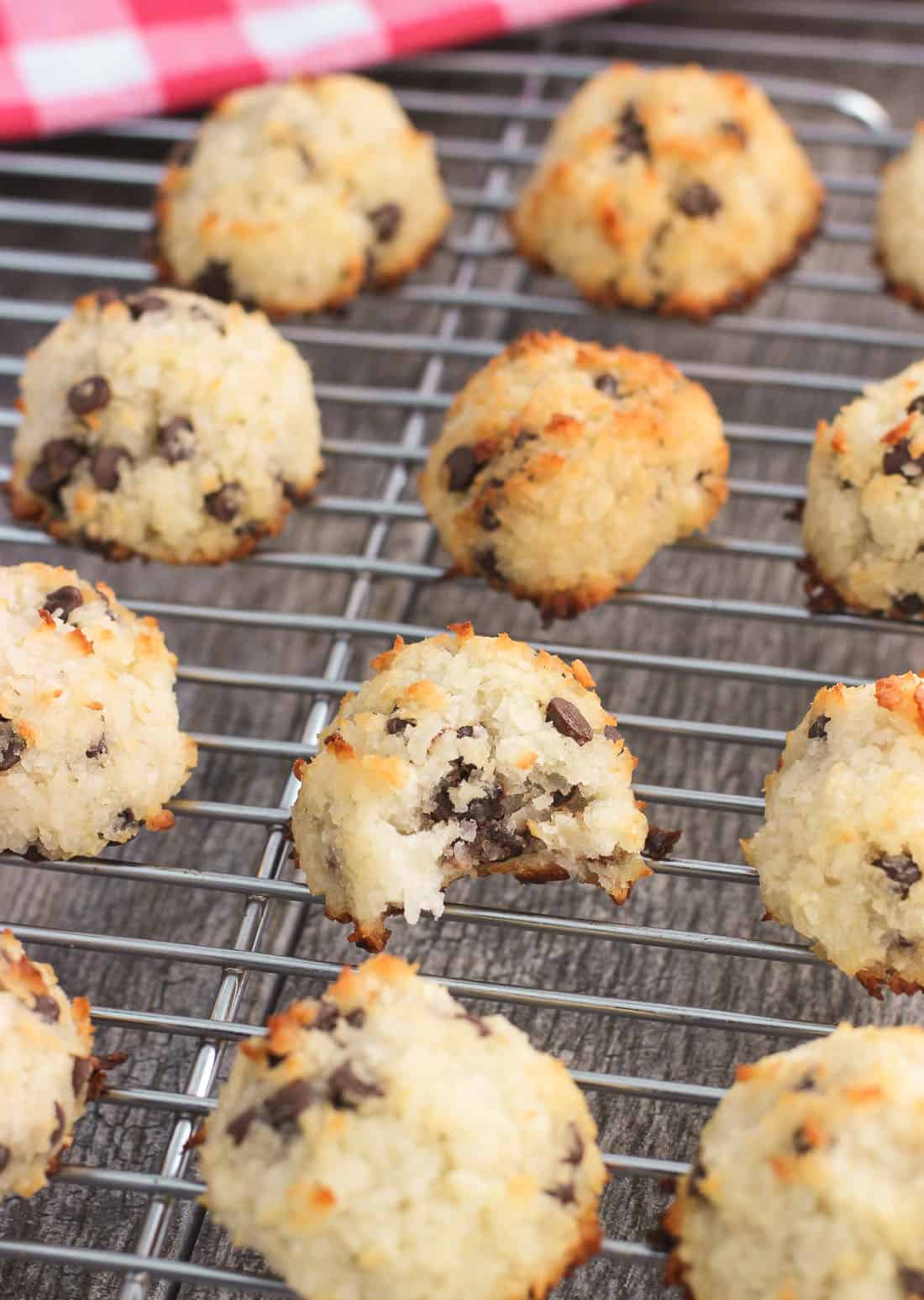 Macaroons cooling on a rack with a bite taken out of the middle macaroon, showing melted chocolate chips in the center of the cookie