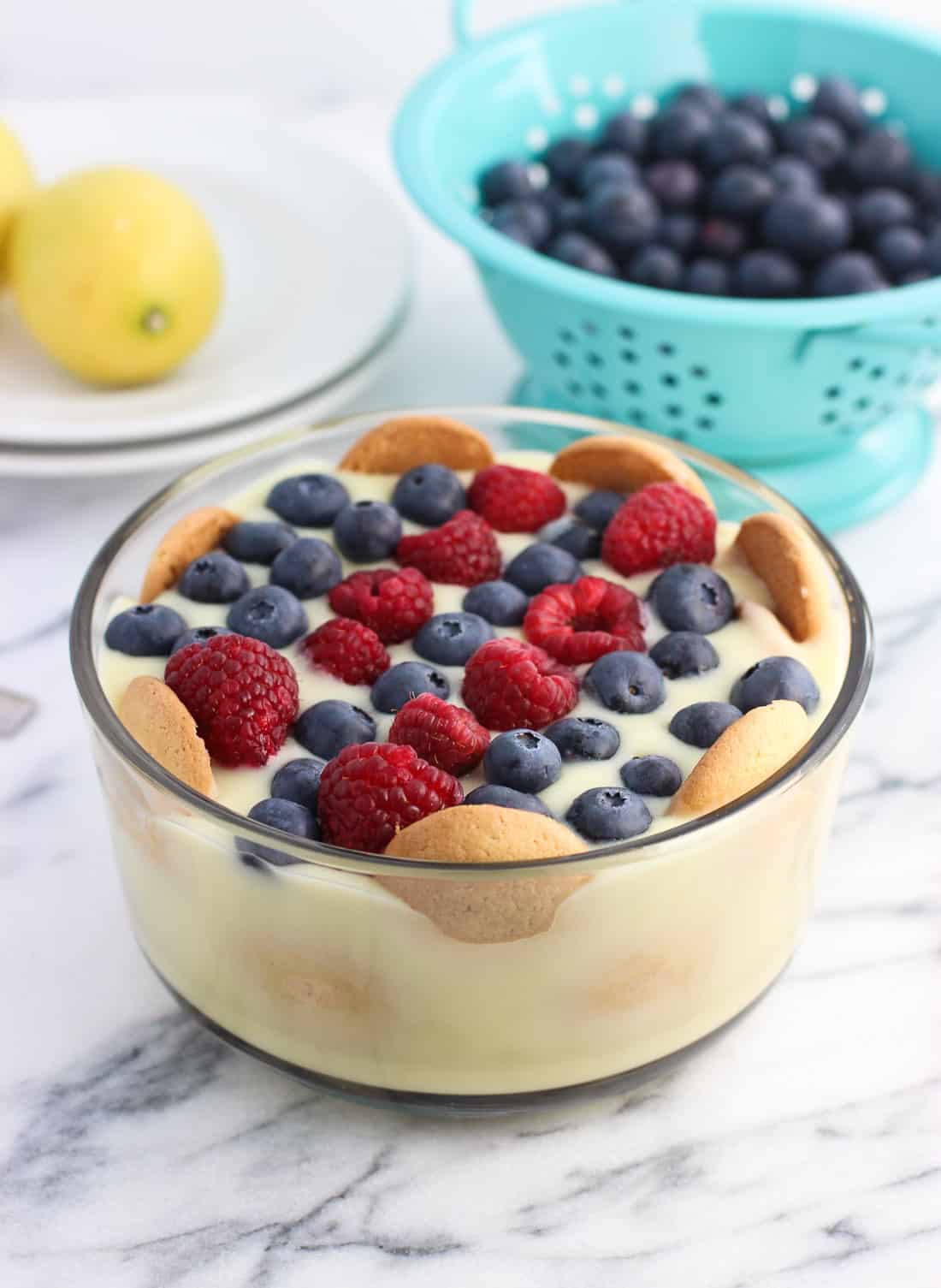 A glass bowl filled with lemon pudding topped with wafers and berries.