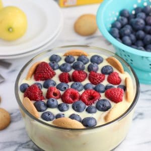 A bowl of lemon pudding layered with vanilla wafers and topped with fresh fruit.