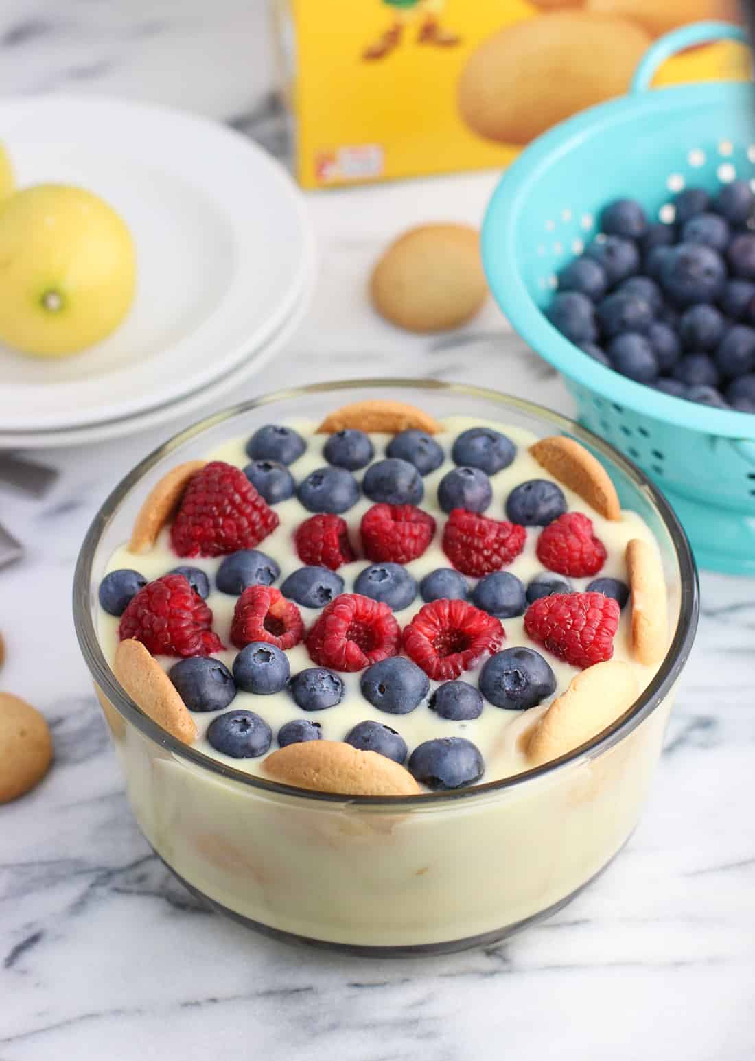 A bowl of lemon pudding layered with vanilla wafers and topped with fresh fruit.