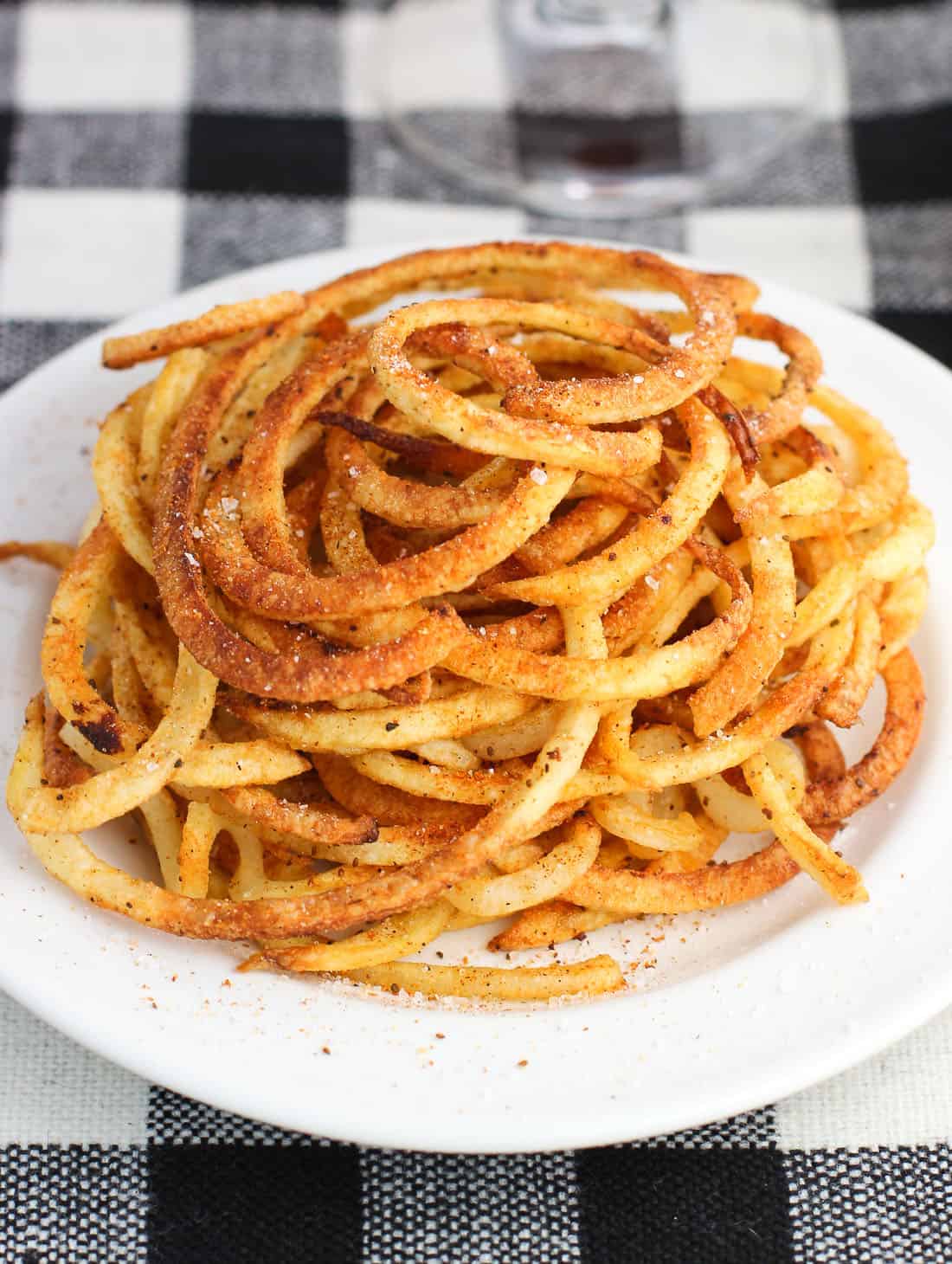 A close up of a plate of seasoned fries.