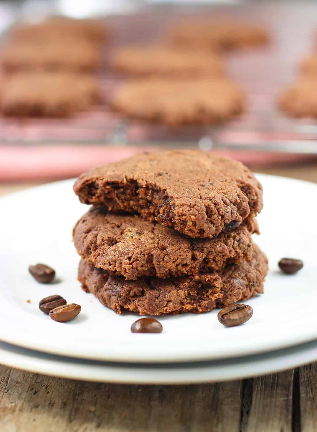 A stack of three cookies on a plate with a bite taken out of the top one.