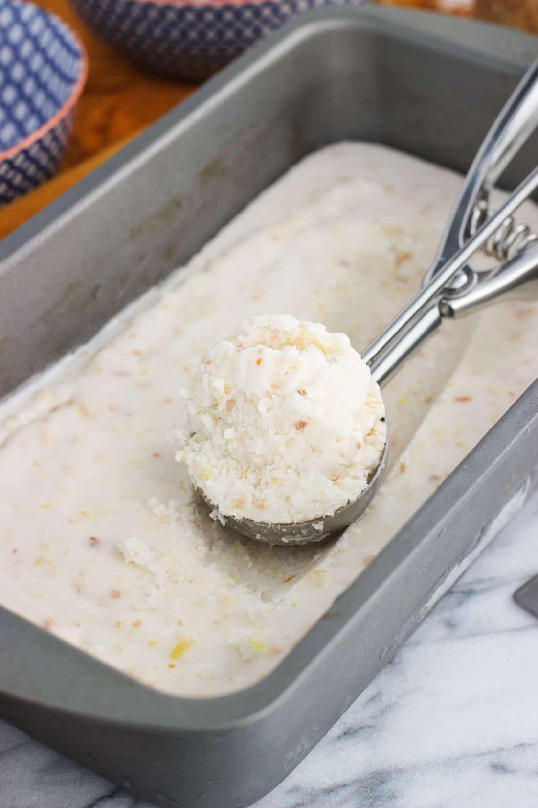 A metal scoop filled with ice cream resting on top of the container.