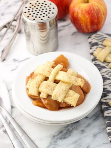 A serving of slow cooker apples on a dessert plate with a lattice pie topping.