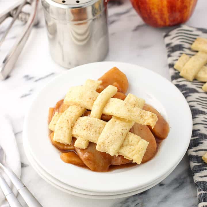 A serving of slow cooker apples on a dessert plate with a lattice pie topping.