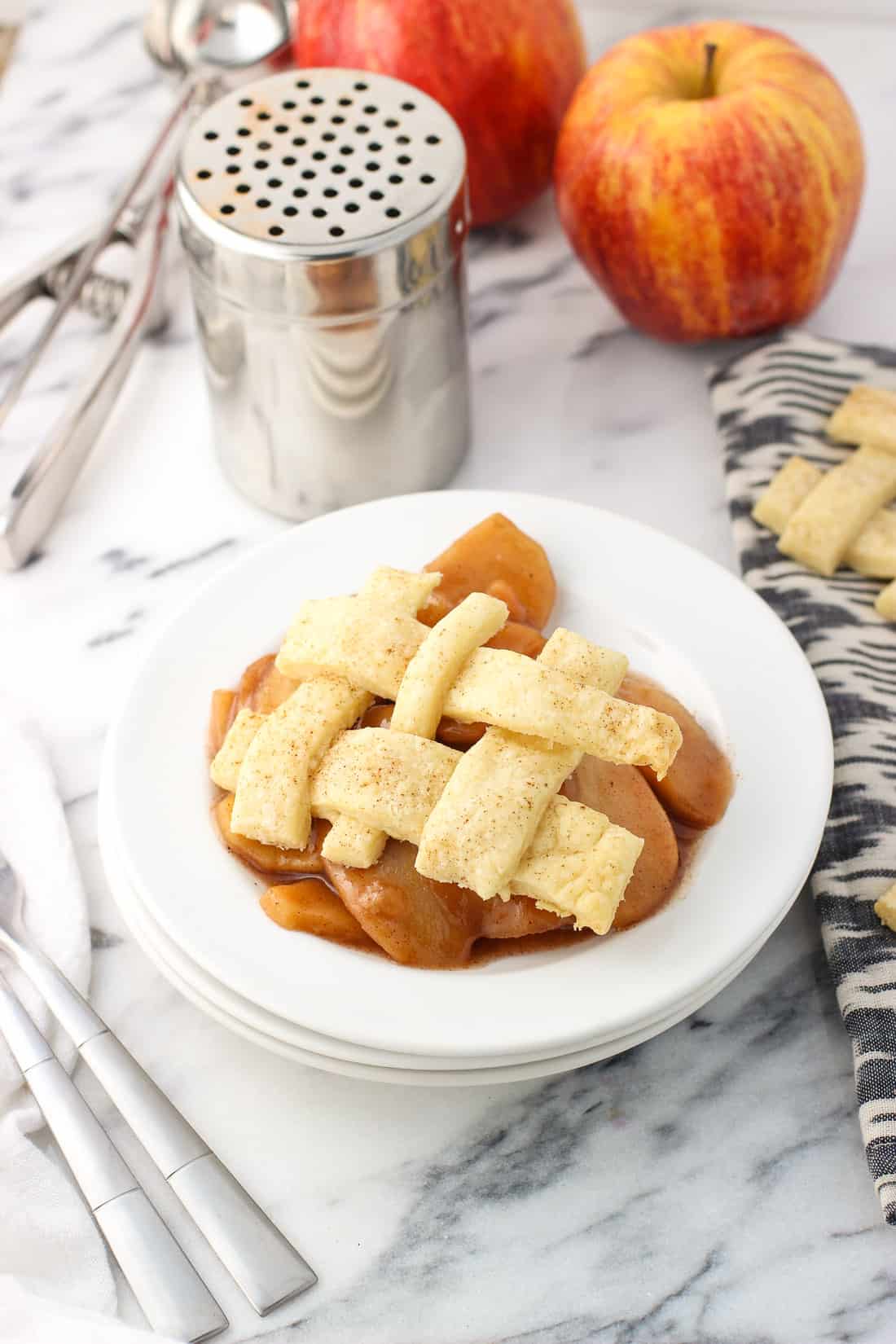 A serving of slow cooker apples on a dessert plate with a lattice pie topping.