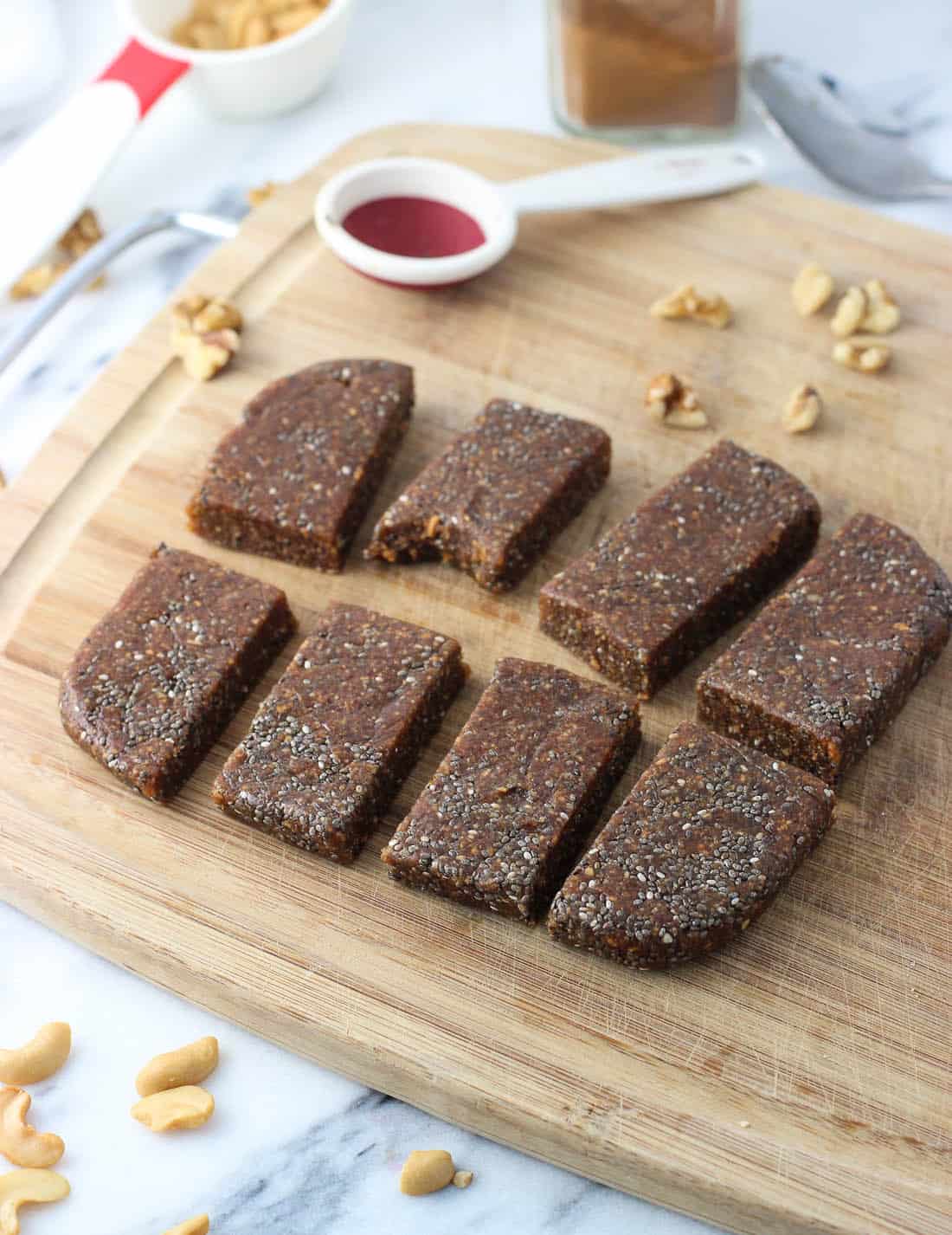 Eight sliced apple cinnamon chia bars on a wooden cutting board.